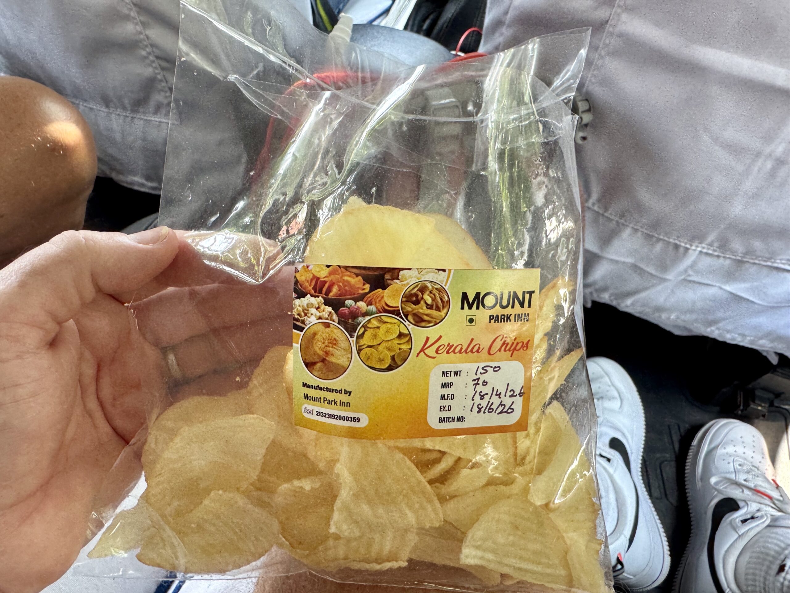 Person holding a clear plastic bag of Kerala chips with a yellow label showing chip images and branding.