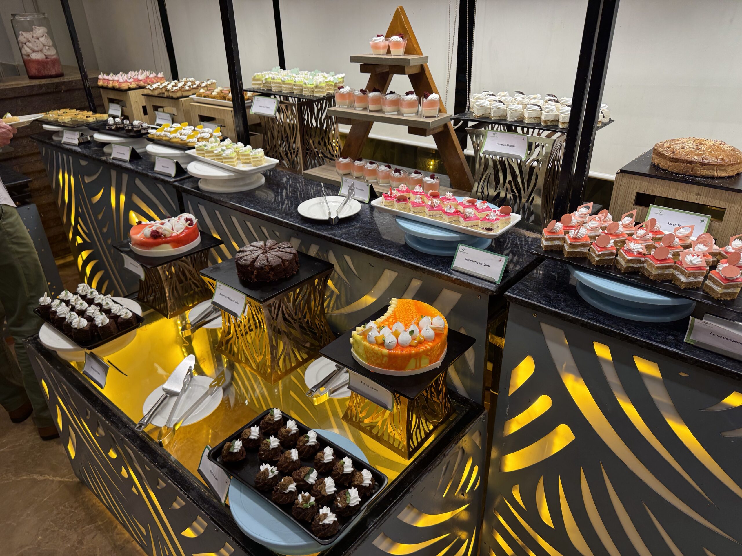 Assorted desserts arranged on a glossy black and gold buffet for a dessert display.